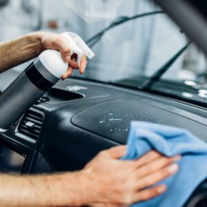 spraying cleaning material to a car dashboard with microfiber towel