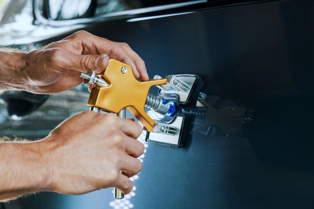 mechanic using a dent puller to a car