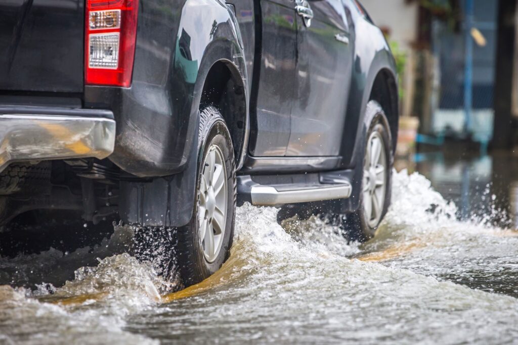 black semi truck passing through a shallow water