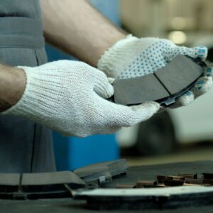 mechanic holding new brake pad set