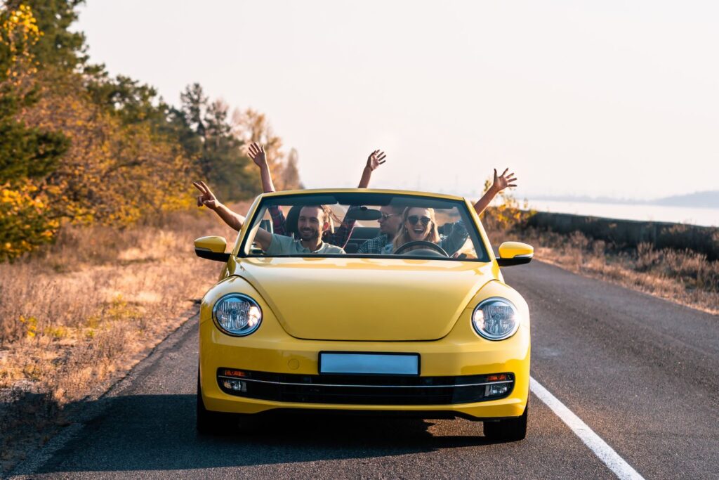 happy group of friends in a yellow car