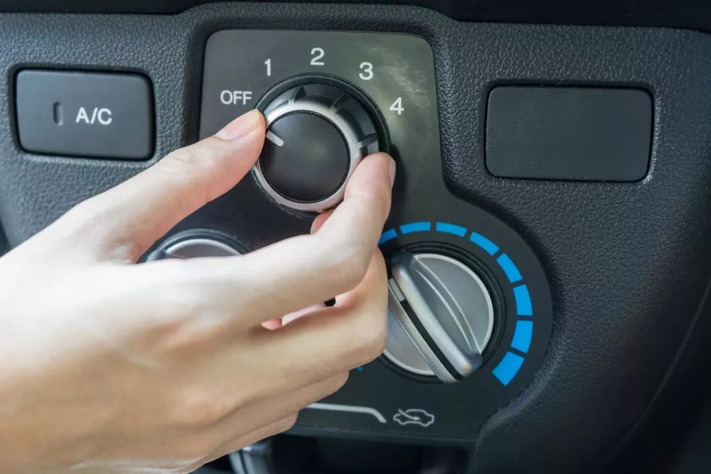 Woman hand turning on car air conditioning system